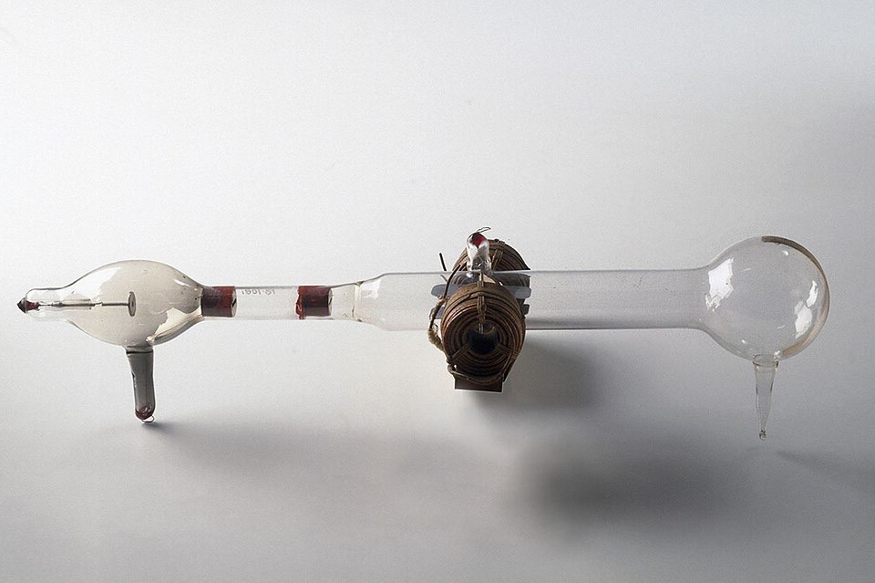 A long glass tube with a bulb at each end and wire coils around the middle