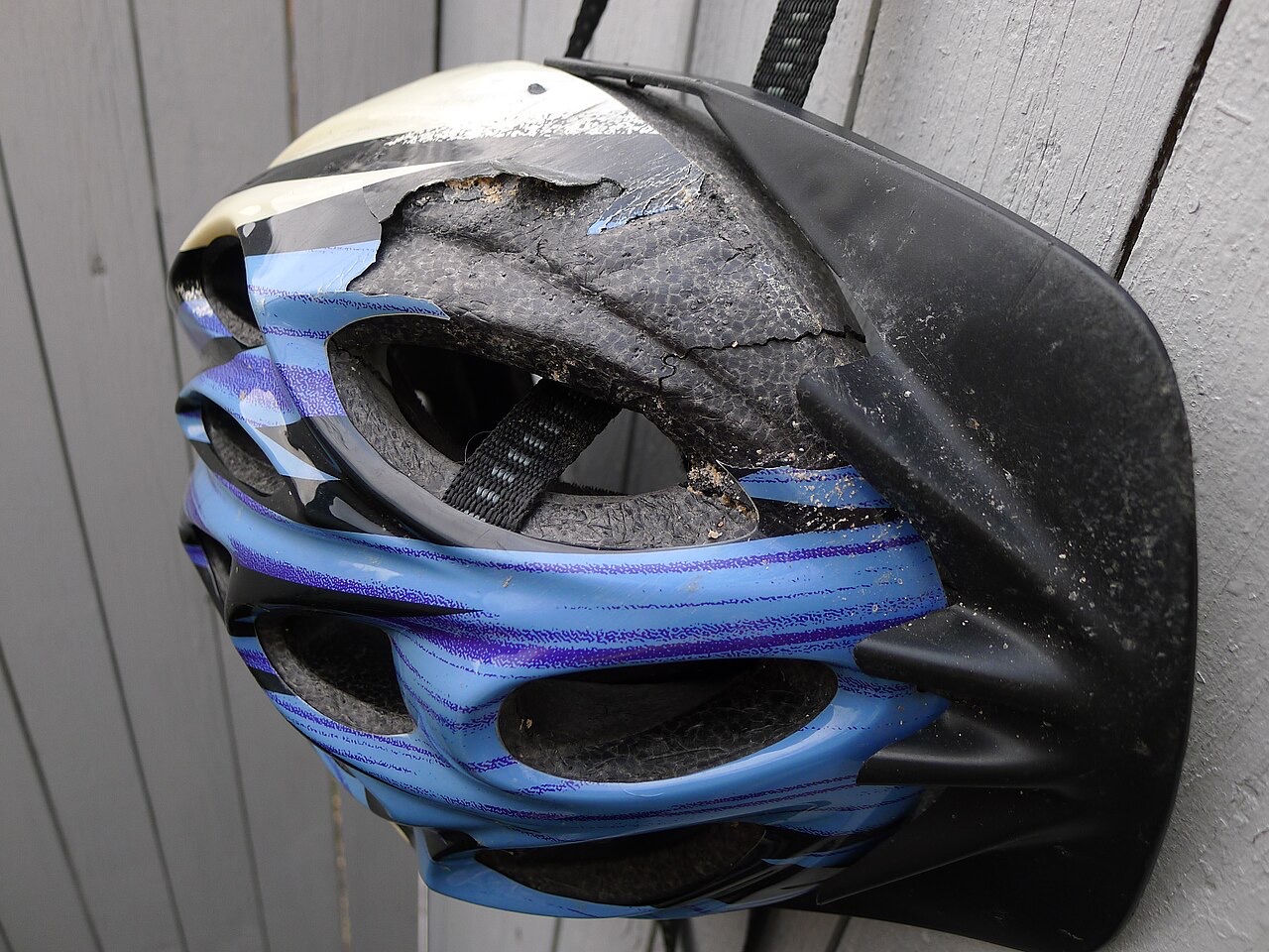 A cycle helmet with its outer shell torn open and the foam underneath cracked and crushed