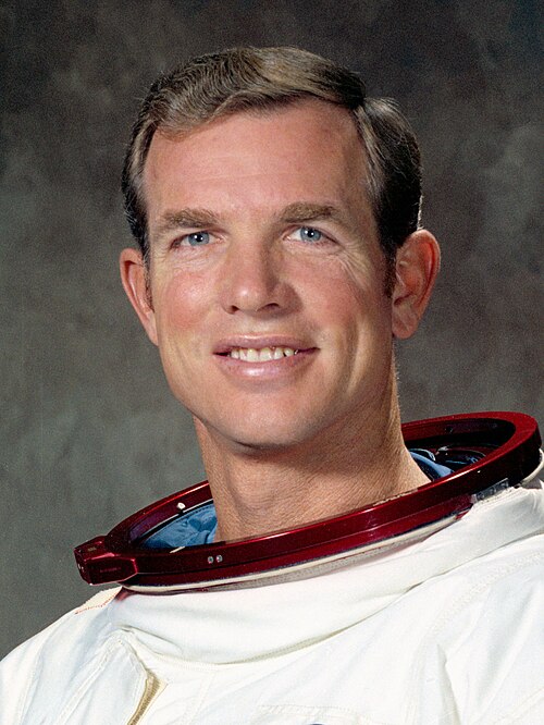 Portrait of astronaut David Scott in a white spacesuit, holding his helmet