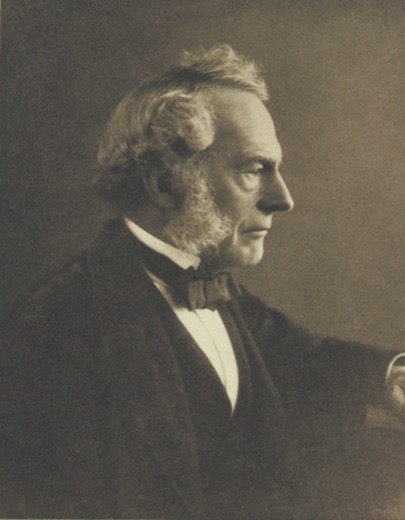 Photograph of George Gabriel Stokes in profile, an older man with white hair and side whiskers, in a dark coat and bow tie