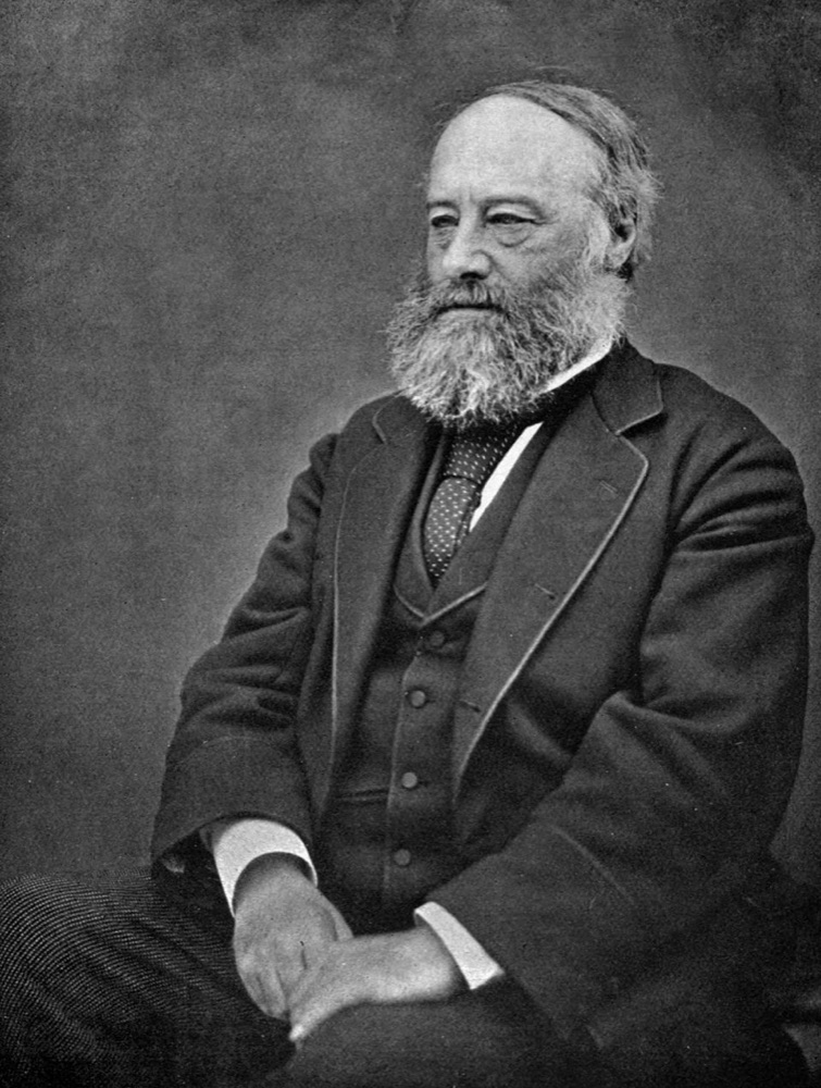 Photograph of James Prescott Joule as an older man with a white beard, seated beside a table