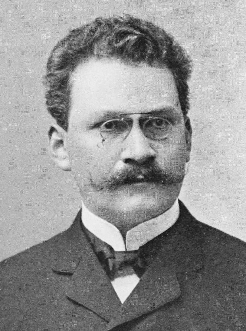 Portrait photograph of Hermann Minkowski, a man with a mustache and pince-nez in a dark suit