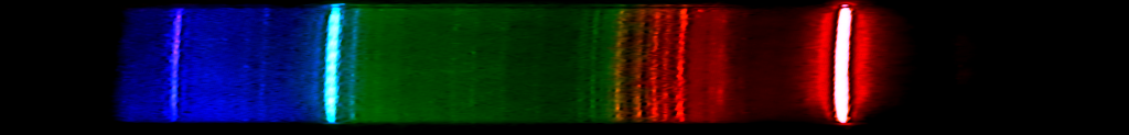 A dark strip crossed by a red line, a blue-green line and violet lines
