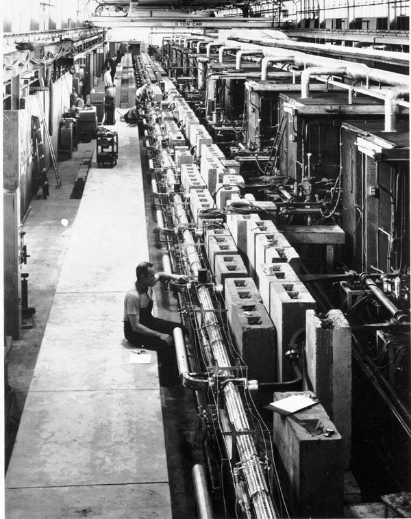 A long straight pipe with equipment along it, running the length of a large hall