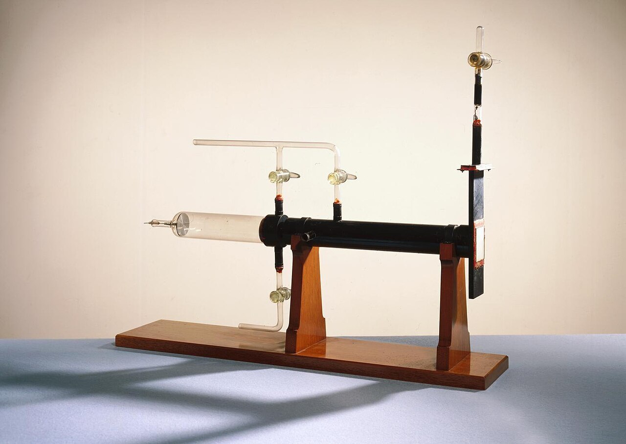 A long glass and metal tube mounted on a wooden stand